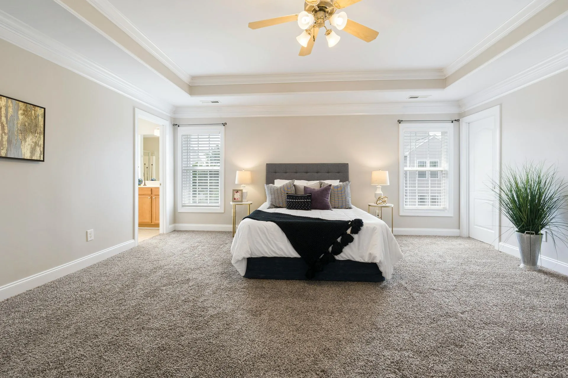 A modern living room with hardwood floors, a dark sofa, a coffee table, and large windows overlooking autumn trees.