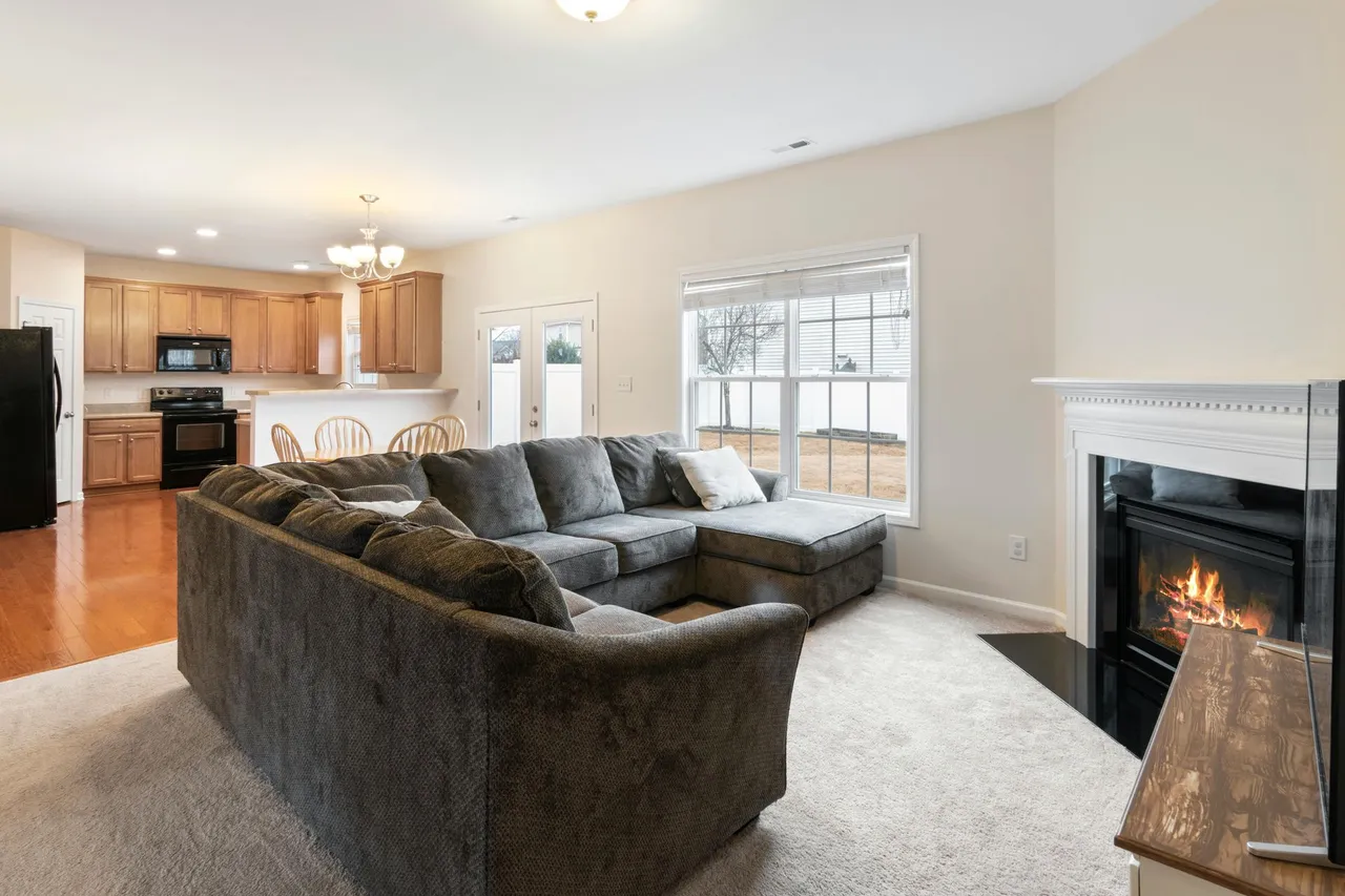 Bright living room with sectional sofa, fireplace, and open kitchen in the background